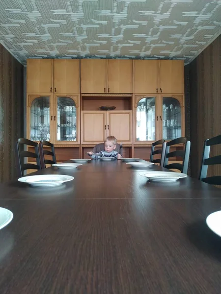 Üzgün yalnız çocuk boş büyük bir yemek masasında oturuyor. Yalnızlık tecrit altında — Stok fotoğraf