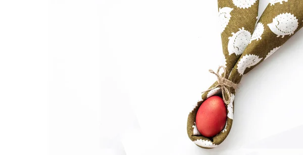 Yeşil peçetedeki kırmızı Paskalya yumurtası doğal iplikle bağlanmış.