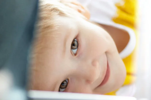 Sarı saçlı, gülümseyen küçük bir çocuğun bakışları.