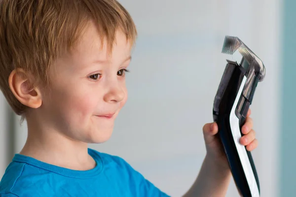 Çocuk gülümser ve elinde bir saç makası tutar.