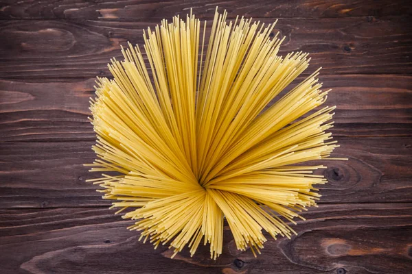 Spaghetti lunghi gialli su sfondo rustico — Foto Stock