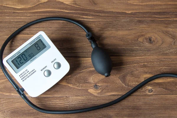 Weißes elektronisches Tonometer auf einem hölzernen Hintergrund. — Stockfoto