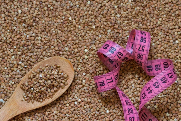 Buckwheat grain, wooden spoon and centimeter or food background — Stock Photo, Image