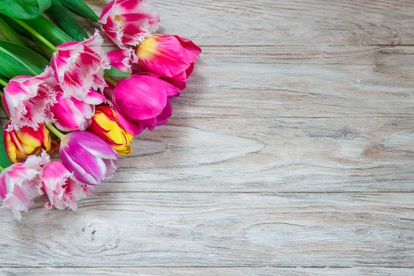 Hermoso fondo floral. Ramo de hermosos tulipanes sobre un fondo de madera . — Foto de Stock