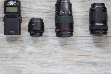 Camera lens well organized over wooden background, top view clipart
