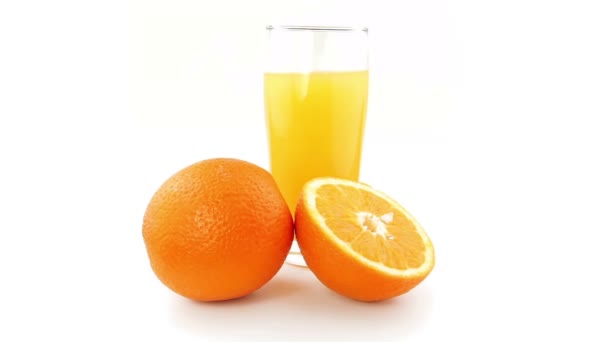 Sinaasappelen en oranje sap roterende op een witte achtergrond — Stockvideo