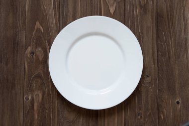 Ahşap arka plan üzerinde beyaz bir seramik tabak