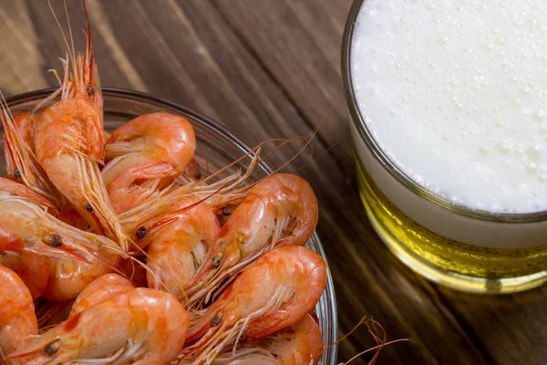 Boiled shrimps in a glass bowl and beer in a glass on wooden background — Stock Photo, Image