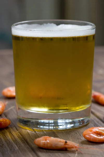 Стакан холодного пива на деревянной поверхности с вареными креветками — стоковое фото