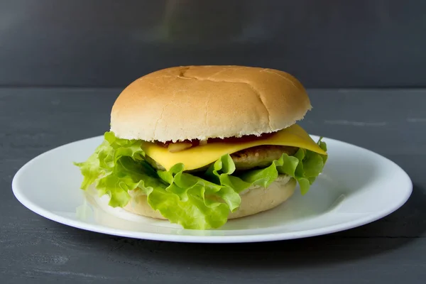 Heerlijke cheeseburger op witte plaat op grijze oppervlak — Stockfoto