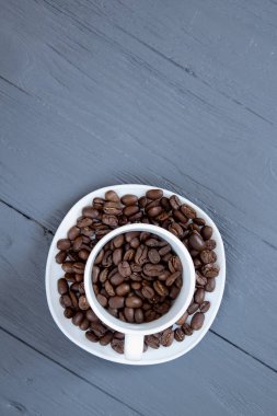 Fincan kahve çekirdekleri içinde izole üzerinde gri ahşap arka plan ile