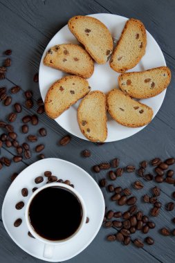 Fincan kahve, dağınık kahve çekirdekleri ve ahşap arka plan üzerinde kızarmış ekmek