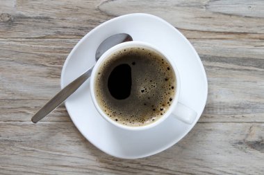 Ahşap arka plan üzerinde izole kaşık ve siyah kahve Kupası