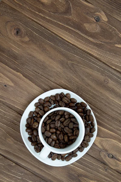 Cup with coffee beans inside isolated on brown wooden background