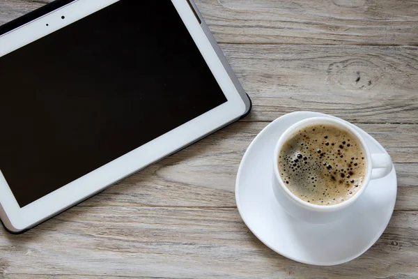 Cup of coffee and tablet on wooden background — Stock Photo, Image