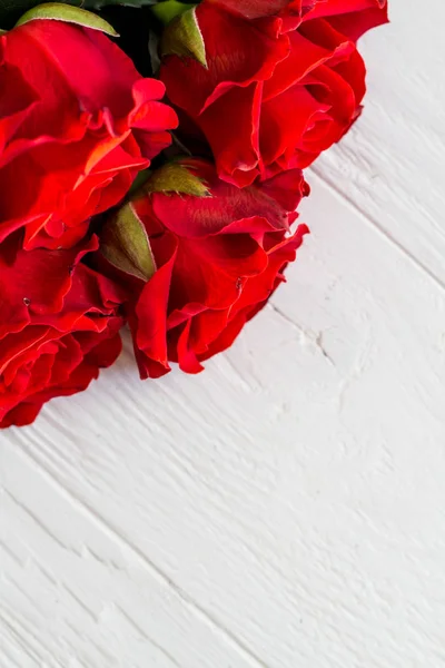 Pocas rosas rojas en una esquina sobre fondo de madera clara con copyspace — Foto de Stock