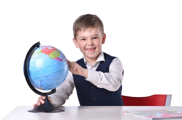 Écolier à l 'bureau rit et pointant sur un globe — Photo