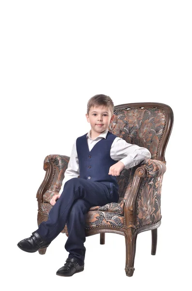 Schoolboy sitting in an antique-designed chair — Stock Photo, Image