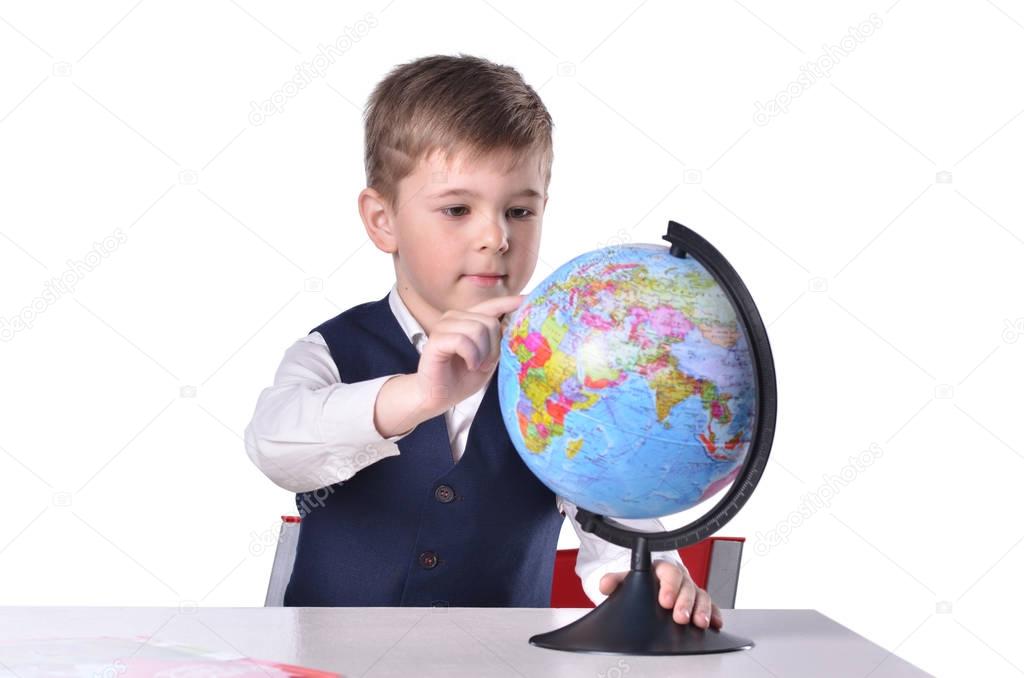 Schoolboy at the desk searching something on a globe of world