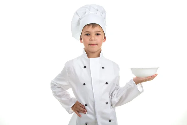 Un bambino con un piatto vuoto sulla mano che indossa l'uniforme da chef, isolato su sfondo bianco . — Foto Stock