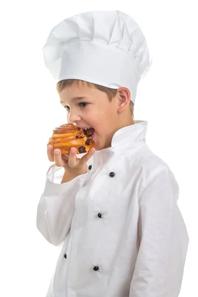 Little cute chef cooker eating delicious fresh raisin bun, isolated on white — Stock Photo, Image