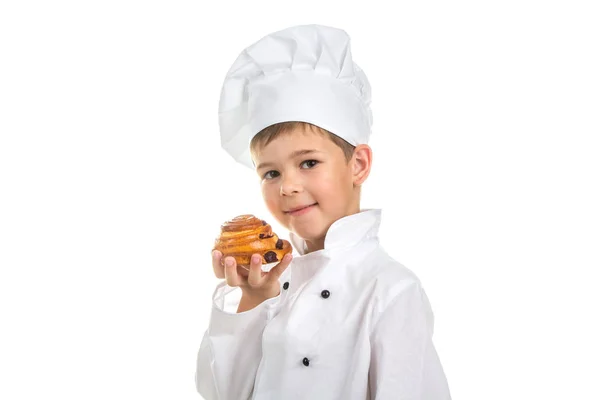 Pequeño chef feliz sosteniendo delicioso bollo de pasas sabroso con una corteza de oro —  Fotos de Stock