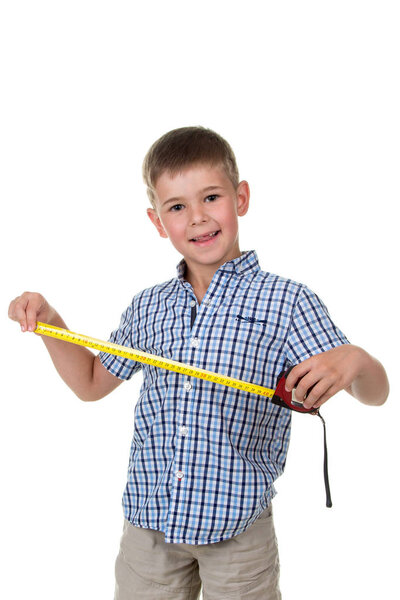 Young builder assistant in blue checkered shirt is happy to measure something with a measuring tape, white background.