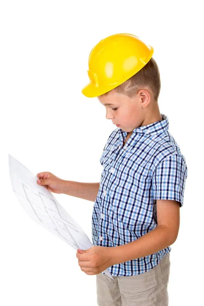 Niño inteligente con casco amarillo y camisa a cuadros azul sosteniendo un plan de papel de construcción en las manos, aislado en blanco — Foto de Stock