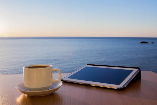 White tablet ipad on table desk with coffee cup, with sea landscape — Stock Photo, Image