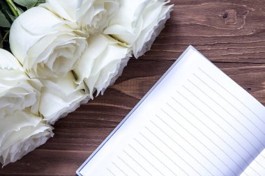 Düğün invintation defter ve beyaz gül ahşap masa üzerinde