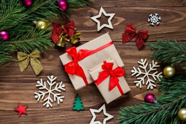 Sevimli Noel armağan çan, kar taneleri, yıldız, Noel topları, çam ağacı dalları, renkli çizgili yay gibi yeni yıl gelin teli ile çevrili ahşap masa üstünde