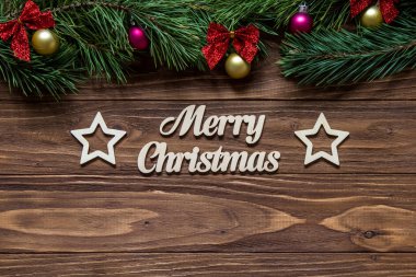 Çam ağacı dalları ve tinsel üstünde ile ahşap arka plan ve iki güzel yıldız ortasına neşeli Noel başlık.