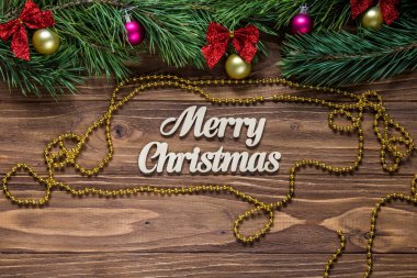 Neşeli Noel başlık tinsel ve çevresinde altın bir çelenk ile ahşap arka plan ortasına.