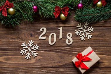 Yeni yıl 2018 orijinal fuar iki güzel kar taneleri ve ekranın üst kısmında çam ağacı dalları ile ahşap arka plan Merkezi'nde bir hediye kutusu