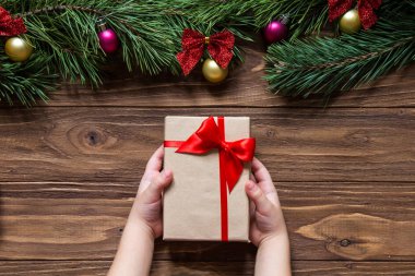 Ekranın üst kısmında çam ağacı dalları ile ahşap arka plan üzerinde güzel bir Noel tema. Childs'ın Noel hediyesi eller, makro.