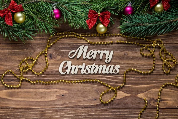 Frohe Weihnachten Titel auf der Mitte des hölzernen Hintergrund mit Lametta und einem goldenen Chaplet herum. — Stockfoto