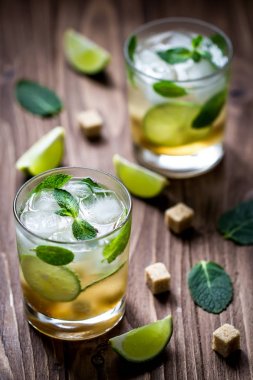 İki limonata bardağı, taze limon, içkiyle buz küpleri ahşap tablo