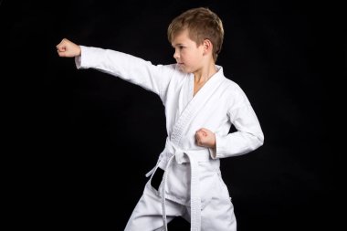 Düz karate vurmak kol. İzole siyah arka plan üzerine yepyeni kimono içinde çocuk