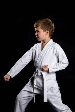 Aşağı yumruk vurmak, karate içinde poz. Kimono siyah arka plan üzerine çocuk