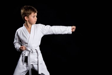 Düz sol el yumruk vurmak, karate içinde poz. Kimono siyah arka plan üzerine çocuk