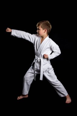 Karate içinde vurmak yumruk. Ciddi izole siyah arka plan üzerine yepyeni kimono çocukta
