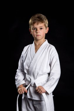 Siyah arka plan üzerine açık konumda yeni kimono ciddi çocukta. Onun kemer tutarak karate avcı