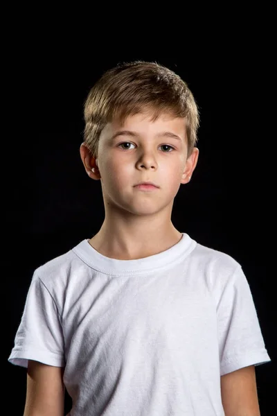 Retrato infantil pensativo, menino inteligente no fundo preto olhando em linha reta — Fotografia de Stock