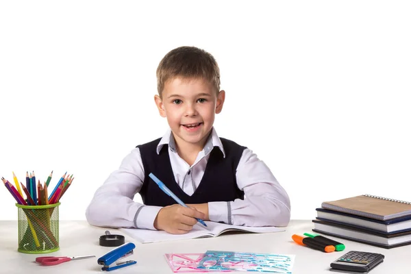 Niedliche fröhliche Schülerin sitzt still am Schreibtisch, umgeben von Schreibwaren — Stockfoto