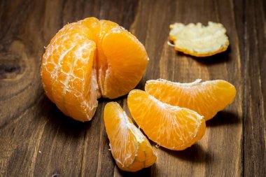 Taze organik mandalina ve rustik ahşap arka plan üzerinde soyulmuş dilimleri