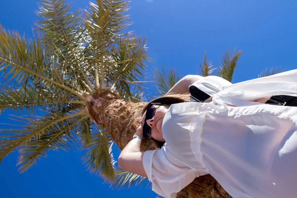 在埃及度假村的棕榈树附近, 一个美丽的高加索年轻女子, 从底部集中注意力, 豪华的风景 图库照片