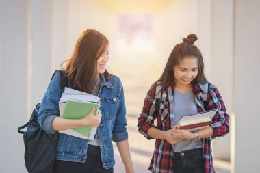 İki Asyalı kız öğrenci sınıfta öğrendikten sonra üniversitede ders kitabının son içeriğini tartışıyorlar. Çalışma ve arkadaşlık konsepti.