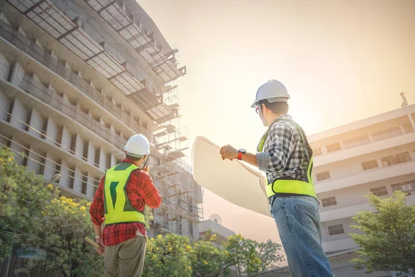 土木技術者は無線通信を使用して建設プロジェクトを制御する 主任技術者は敷地内の建物の建設管理について話し合った — ストック写真