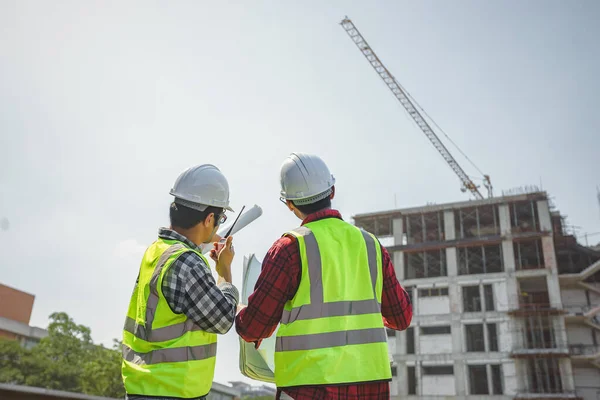 土木技術者は無線通信を使用して建設プロジェクトを制御する 主任技術者は敷地内の建物の建設管理について話し合った — ストック写真