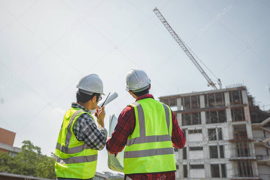 Civil engineers control the construction project by using radio communication. The chief engineer discussed the construction control of the building on the site.